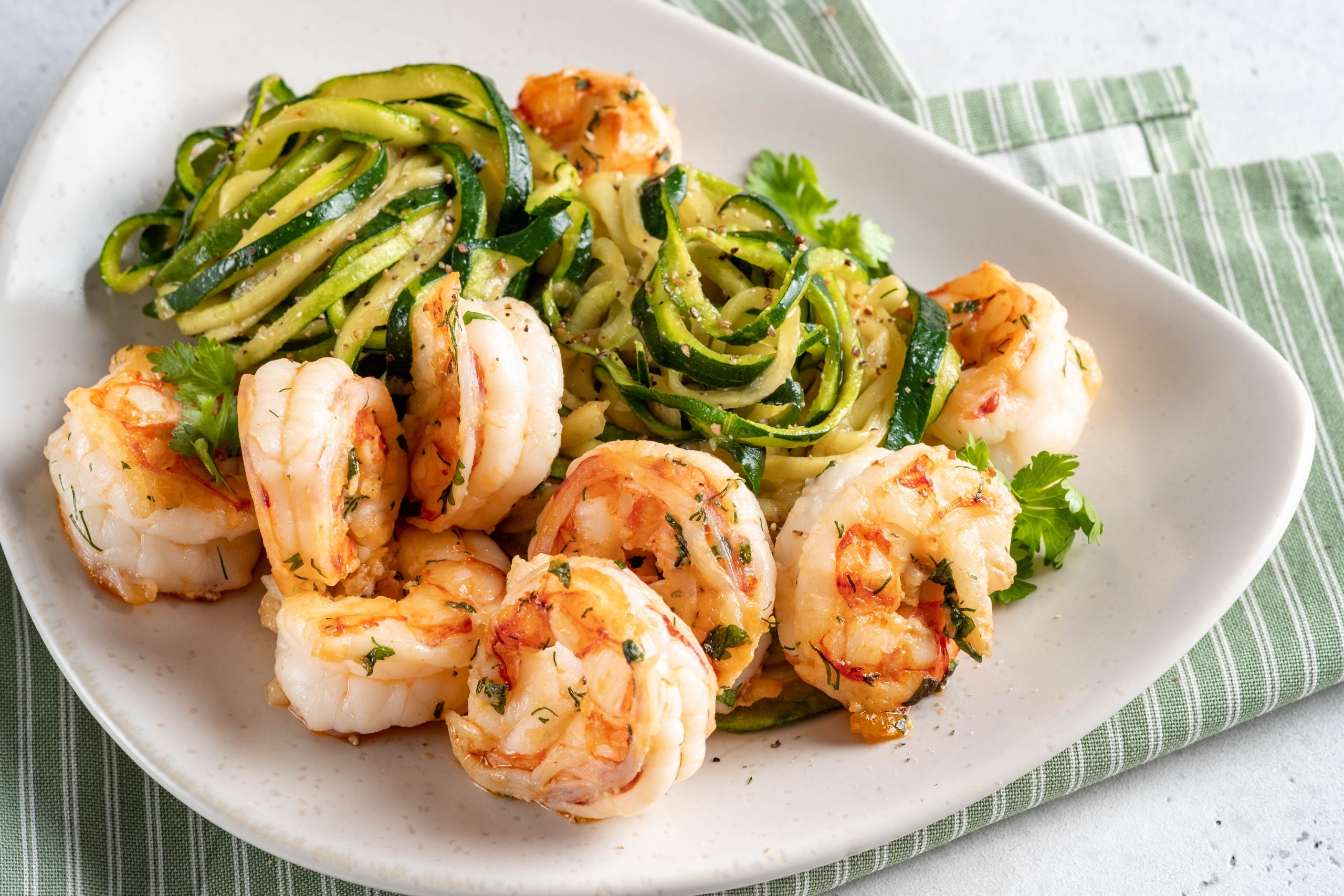 zucchini pasta with shrimps on white plate